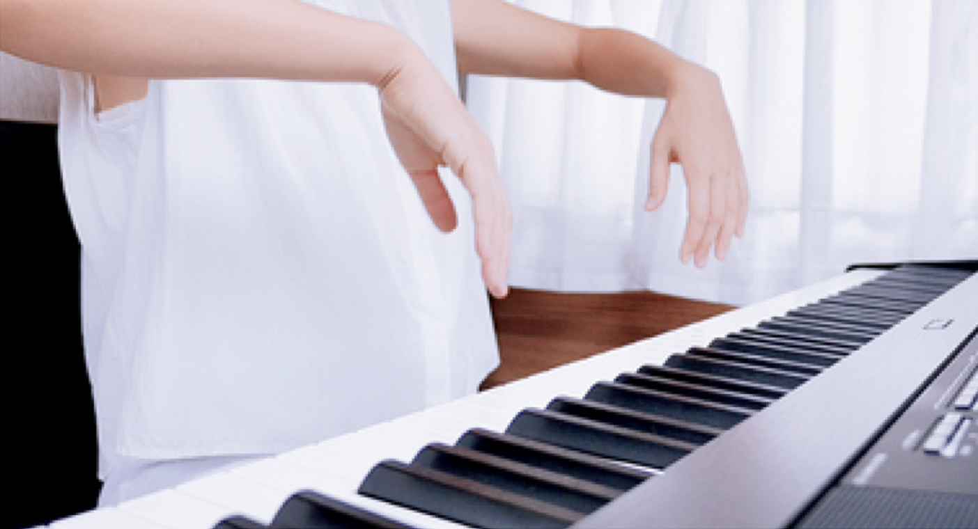 A pianist with both elbows raised out to the sides and hands lifted up away from the keyboard.
